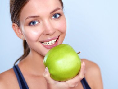 Mutlu genç kadın elma yiyor, beyaz arka planda soyutlanmış.