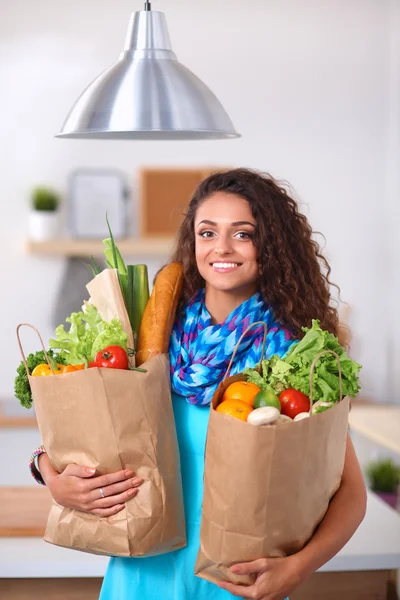 Young woman holding grocery shopping bag with vegetables .Standing in the kitchen