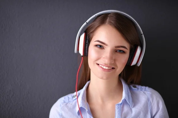 Ragazza sorridente con le cuffie seduto sul pavimento vicino al muro — Foto Stock