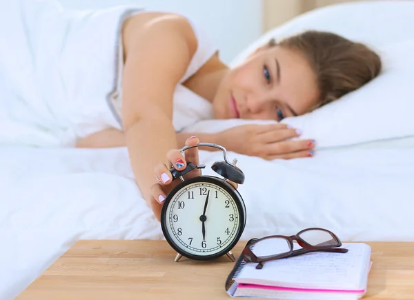 Una mujer joven apagando su despertador por la mañana — Foto de Stock