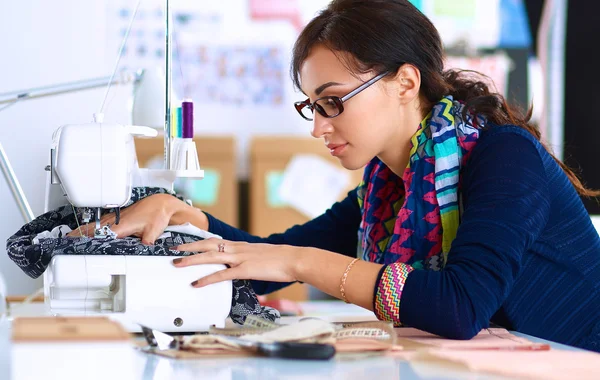 Young woman sewing while sitting at her working place — Stock Photo, Image