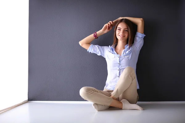 Mujer joven sentada en el suelo cerca de la pared oscura — Foto de Stock