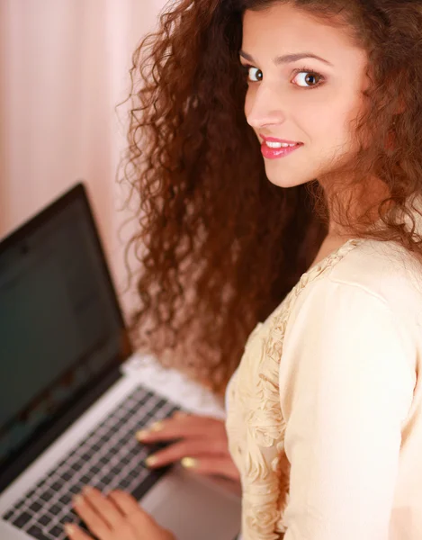 Eine junge Frau mit Laptop sitzt isoliert auf weißem Hintergrund — Stockfoto