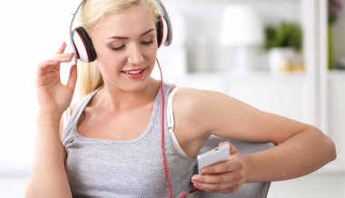 Evdeki genç ve güzel kadın kanepede oturup müzik dinliyor.