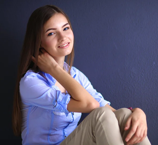 Young woman sitting on the floor near dark wall — Stock Photo, Image