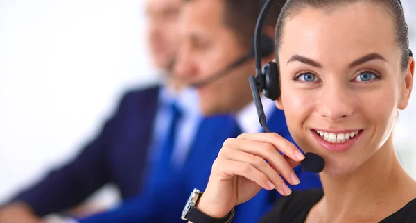 Retrato de mujer de negocios hermosa en auriculares sonriendo con colegas de fondo — Foto de Stock