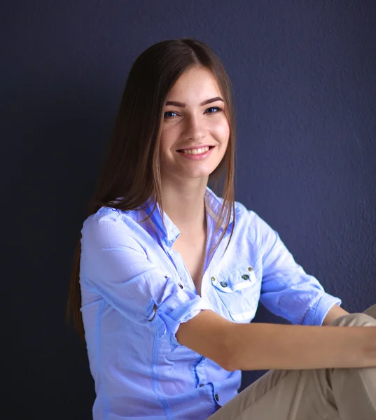 Young woman sitting on the floor near dark wall — Stock Photo, Image