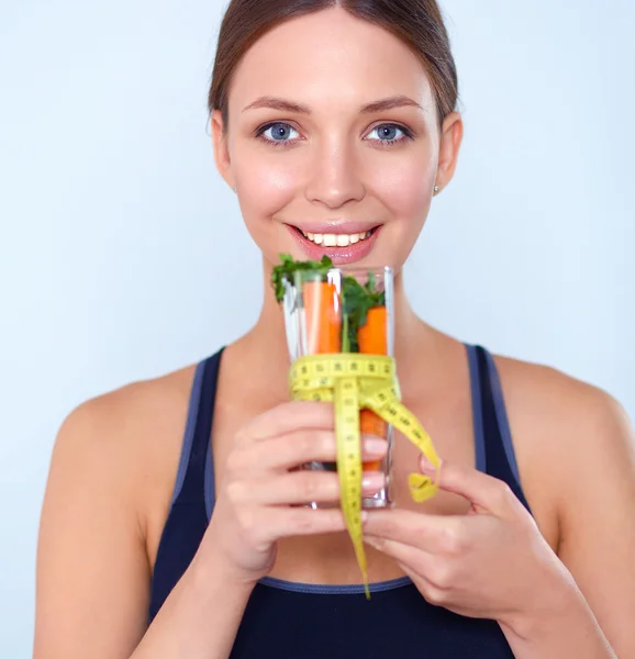 Woman holding a drinking glass full of fresh fruit salad with a tape measure around the glass — Stock Photo, Image