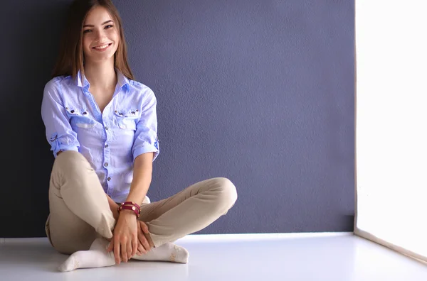 Young woman sitting on the floor near dark wall — Stock Photo, Image