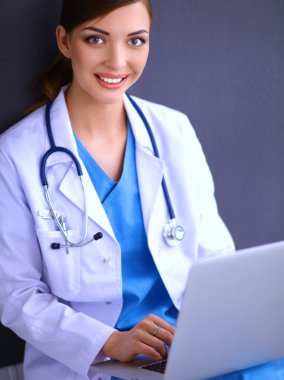 Gri arka planda oturan kadın doktor