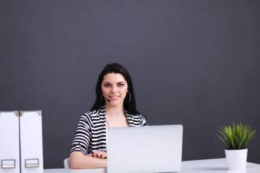 Masasında kulaklığı ve laptopuyla çalışan güzel bir iş kadını.