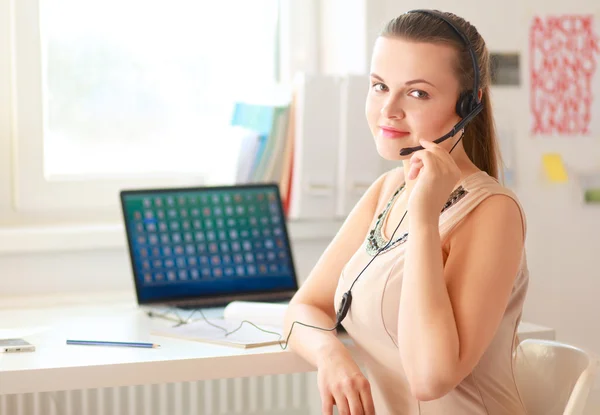 Vacker affärskvinna som arbetar vid sitt skrivbord med headset och laptop — Stockfoto