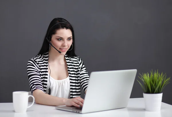 Mulher de negócios bonita trabalhando em sua mesa com fone de ouvido e laptop — Fotografia de Stock