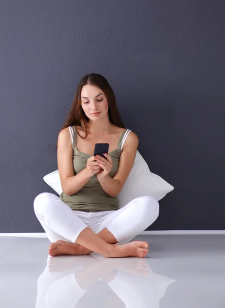 Menina caucasiana atraente sentado no chão com telefone — Fotografia de Stock