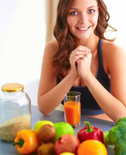 Chica sentada en la cocina en el escritorio con frutas y vasos con jugo —  Fotos de Stock