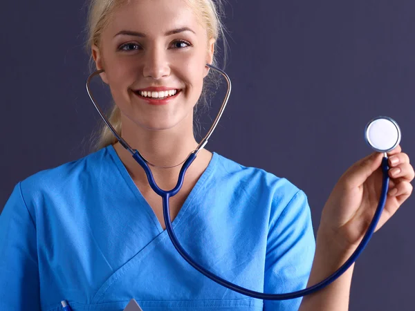 Vrouwelijke arts met een stethoscoop luisteren, geïsoleerd op grijze achtergrond — Stockfoto
