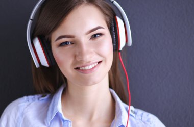 Duvara yakın katta oturan kulaklıklar ile gülümseyen kız