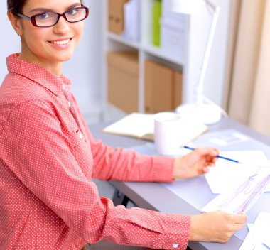 Ofis masasında çalışan genç, çekici bayan moda tasarımcısı, cep telefonuyla konuşurken çizim yapıyor.