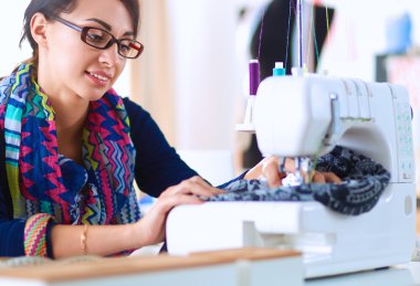 Çalışırken dikiş diken genç bir kadın.