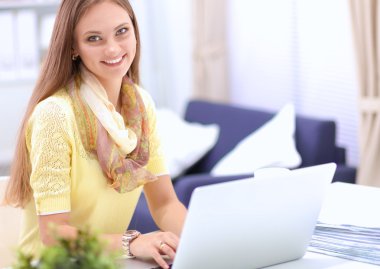 Elinde evrakları olan kadın masanın üstünde oturuyor.