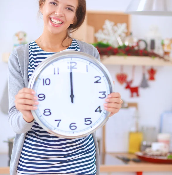 Happy young woman showing clock in christmas decorated kitchen — Stock Photo, Image