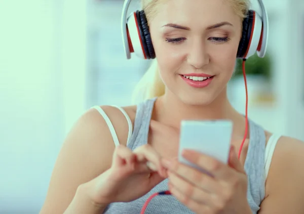 Joven hermosa mujer en casa sentada en el sofá y escuchando música — Foto de Stock