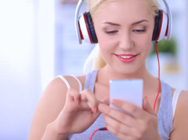 Jonge mooie vrouw thuis zitten op de bank en luisteren muziek — Stockfoto