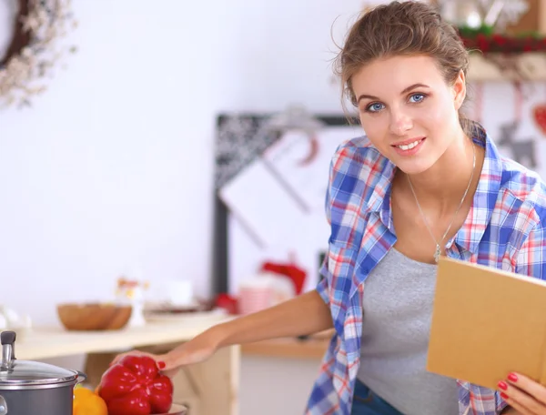 Glimlachende jonge vrouw in de keuken, geïsoleerd op kerst achtergrond — Stockfoto