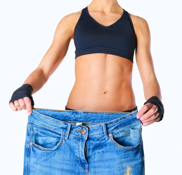 Tineri fitness femeie care arată că ei vechi blugi — Fotografie, imagine de stoc