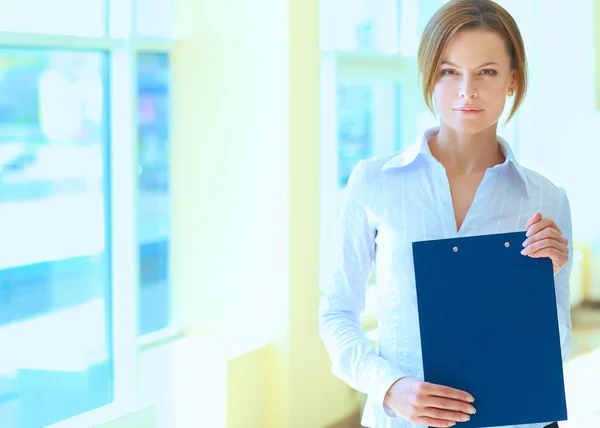 Business woman standing in foreground with a folder in her hands — Stock Photo, Image