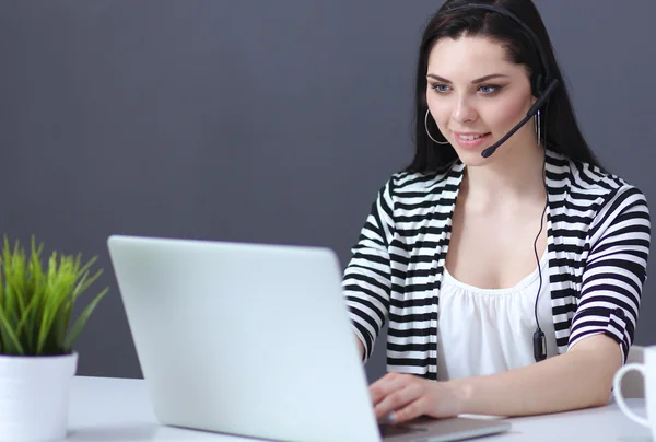 Mulher de negócios bonita trabalhando em sua mesa com fone de ouvido e laptop — Fotografia de Stock