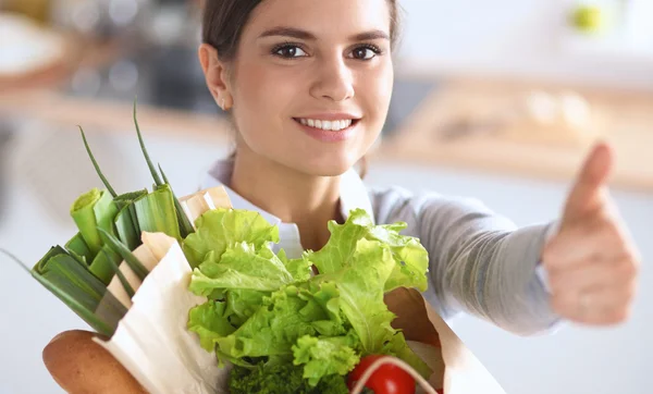 Mujer joven sosteniendo bolsa de la compra de comestibles con verduras y mostrando ok — Foto de Stock