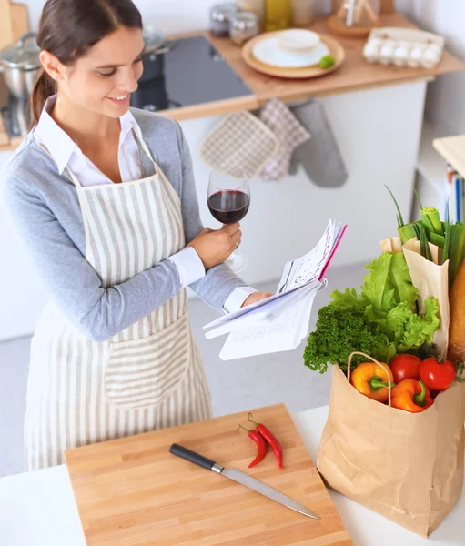 Vrouw met boodschappentassen in de keuken thuis, bij het bureau — Stockfoto