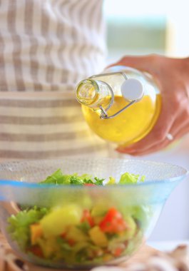 Gülümseyen genç kadın taze salata hazırlıyor.