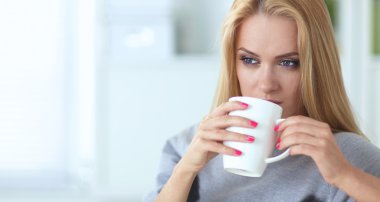 evde kanepenin üzerine bir fincan genç güzel kadın