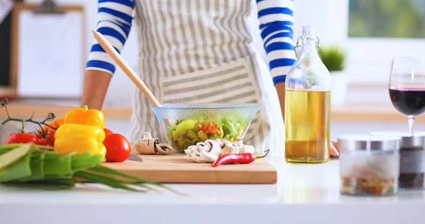 Young woman  mixing fresh salad, standing near desk — Stock Photo, Image