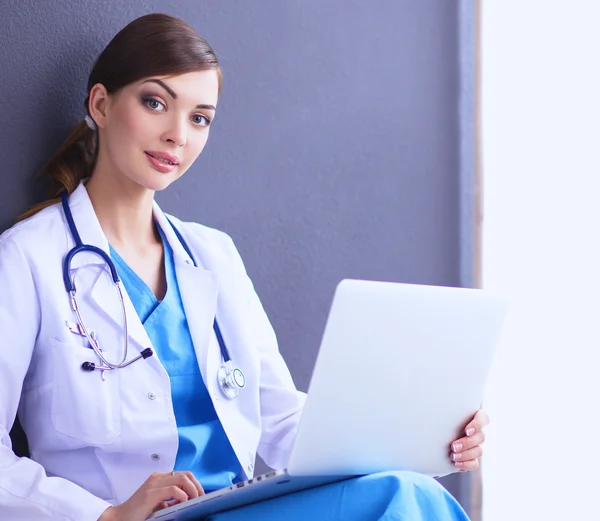 Médico femenino trabajando sentado sobre fondo gris — Foto de Stock