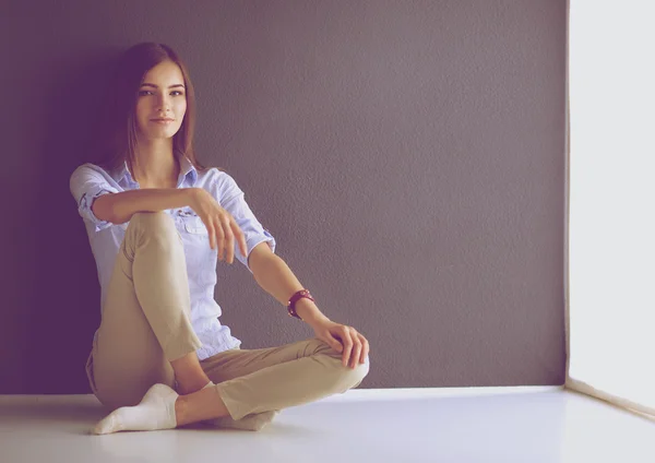 Jovem mulher sentada no chão perto da parede escura — Fotografia de Stock