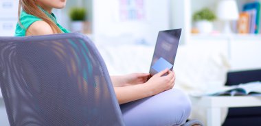 Elinde evrakları olan kadın masanın üstünde oturuyor.