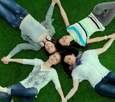 Dört genç kadın yeşil çim üzerinde yalan