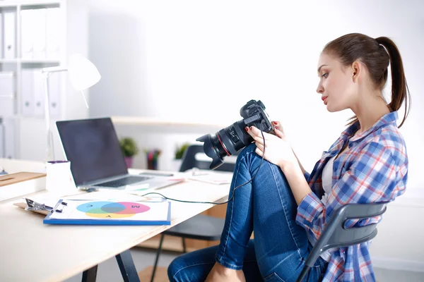 Женщина-фотограф сидит на столе с ноутбуком — стоковое фото