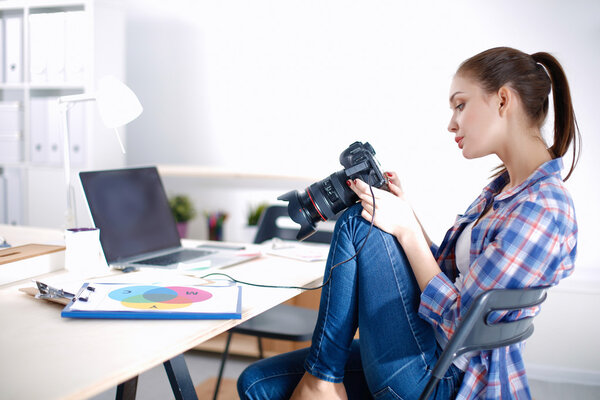 Женщина-фотограф сидит на столе с ноутбуком