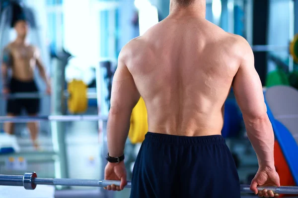 Joven levantando la barra en el gimnasio con instructor — Foto de Stock