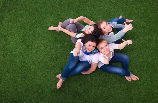 Quatro jovens mulheres sentadas na grama verde — Fotografia de Stock