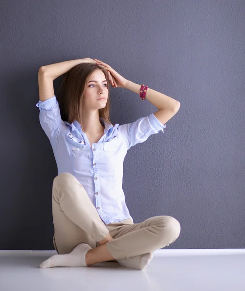 Jeune femme assise sur le sol près du mur sombre — Photo