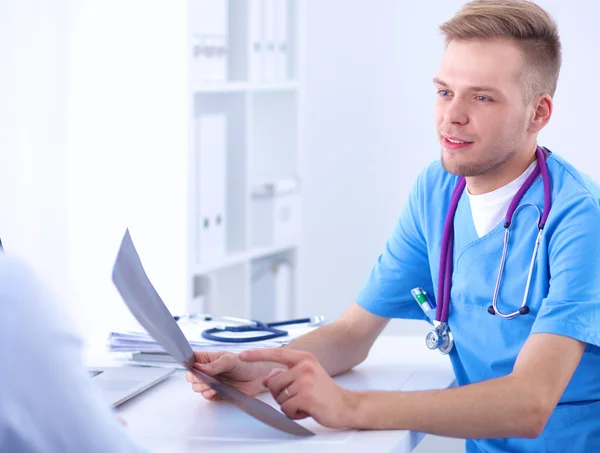 Portret van een lachende mannelijke arts met laptop aan het bureau in medisch kantoor — Stockfoto