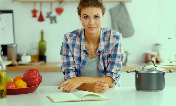 Glimlachende jonge vrouw in de keuken, geïsoleerd op kerst achtergrond — Stockfoto