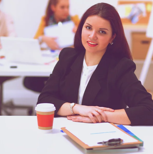 Attractive businesswoman sitting  on desk in the office with cup of coffee — Stock Photo, Image