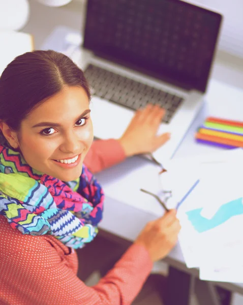 Young attractive female fashion designer working at office desk, drawing while talking on mobile — Stock Photo, Image