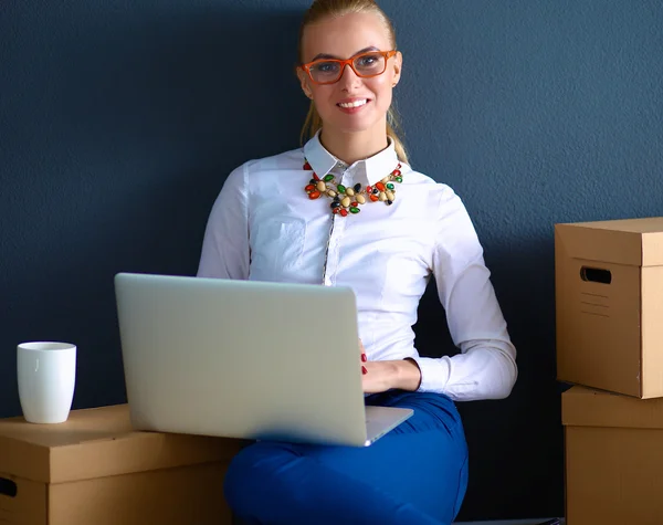 Woman sitting on the floor near a boxes  with laptop — Stock Photo, Image